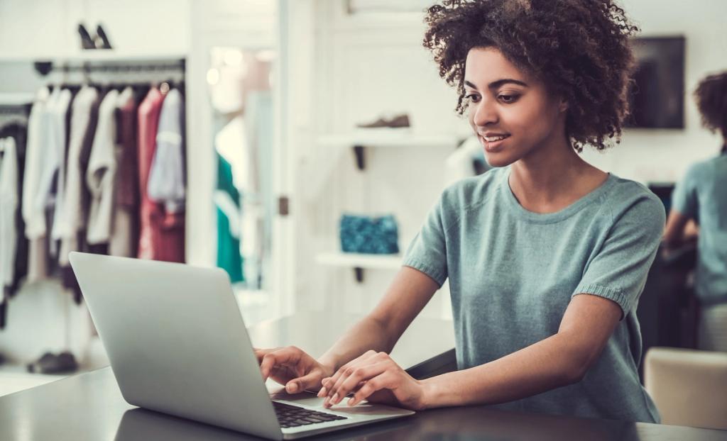 Shop owner working on a laptop at a table in a clothing boutique
