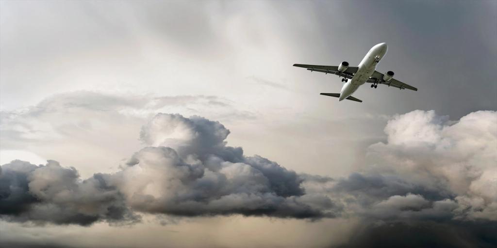 Passenger jet flying low against a sky of heavy gray storm clouds
