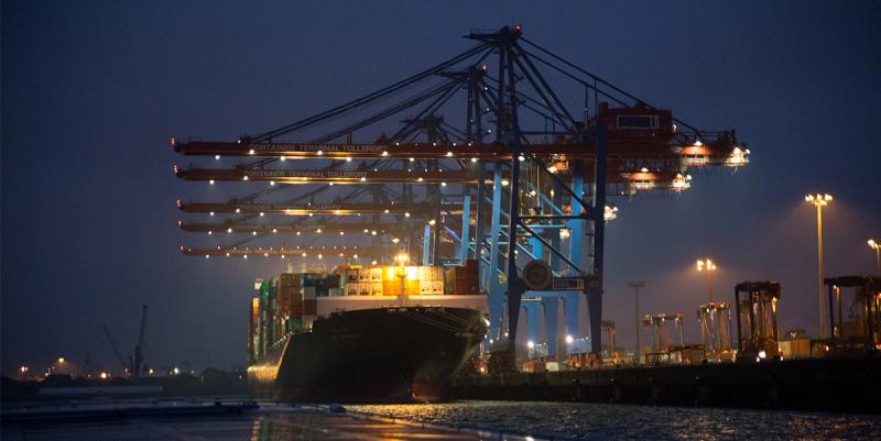 Container terminal at dusk with illuminated ship-to-shore gantry cranes loading a vessel labeled Container Terminal Tollerort