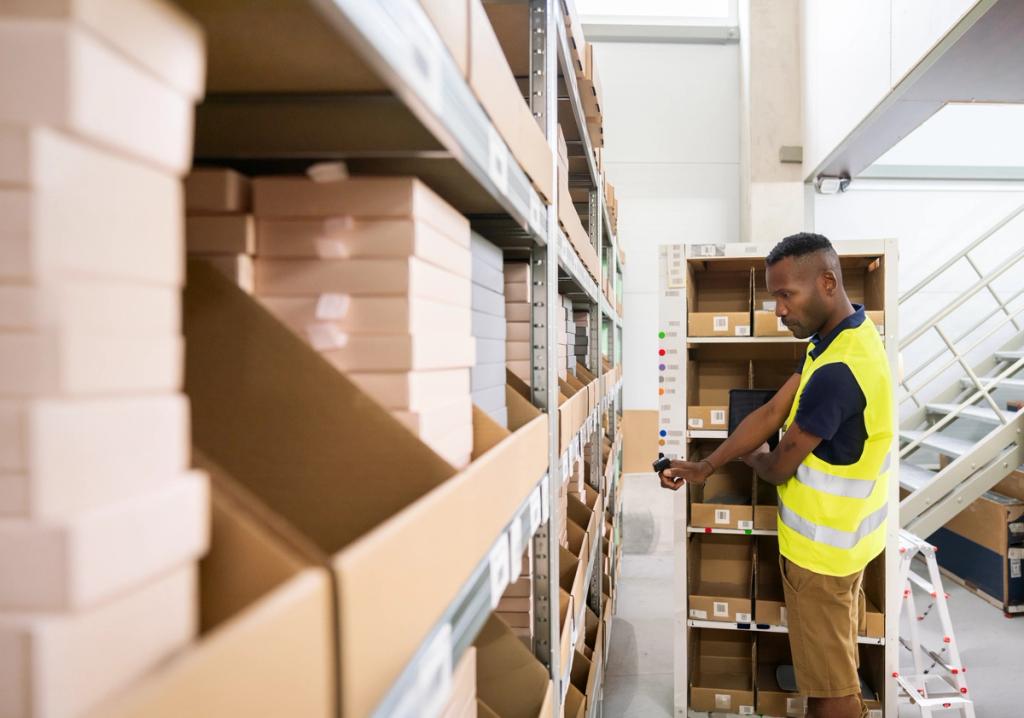 Warehouse worker in safety vest checking items on shelves while holding a handheld device.