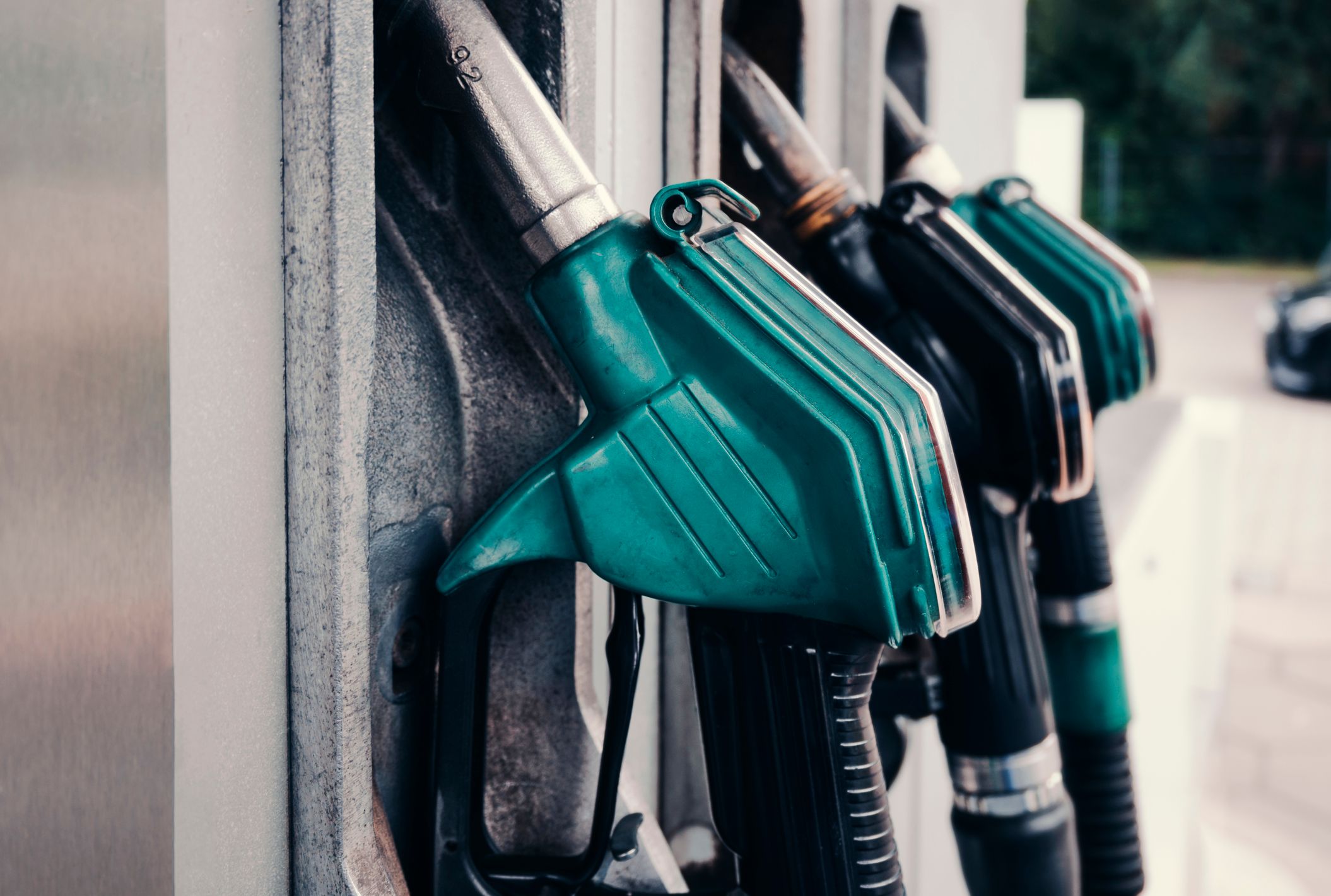 Fuel pump nozzles hanging from dispensers at a gas station.