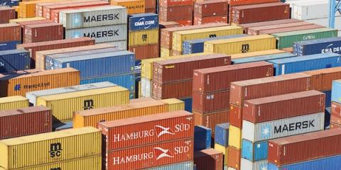 Aerial view of stacked Maersk, Hamburg Sud, CMA CGM and MSC shipping containers in a port yard