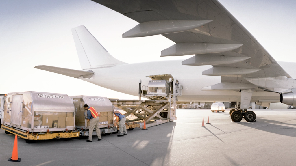 Cargo containers being loaded onto a large transport aircraft using ground equipment.