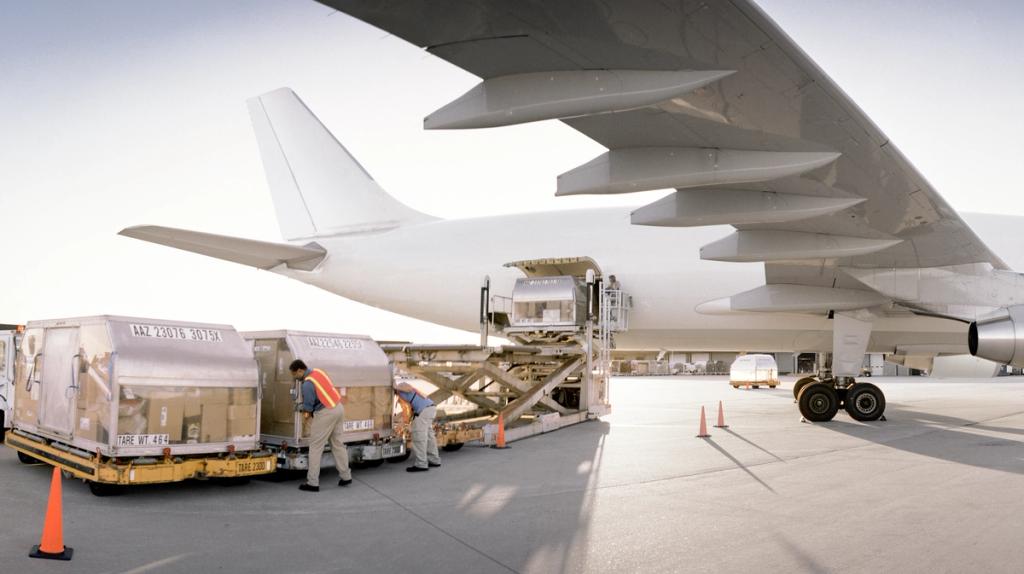Cargo containers being loaded onto a large transport aircraft using ground equipment.