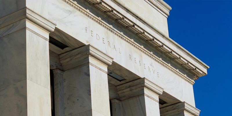 Marble facade of the U.S. Federal Reserve building with FEDERAL RESERVE inscription against blue sky
