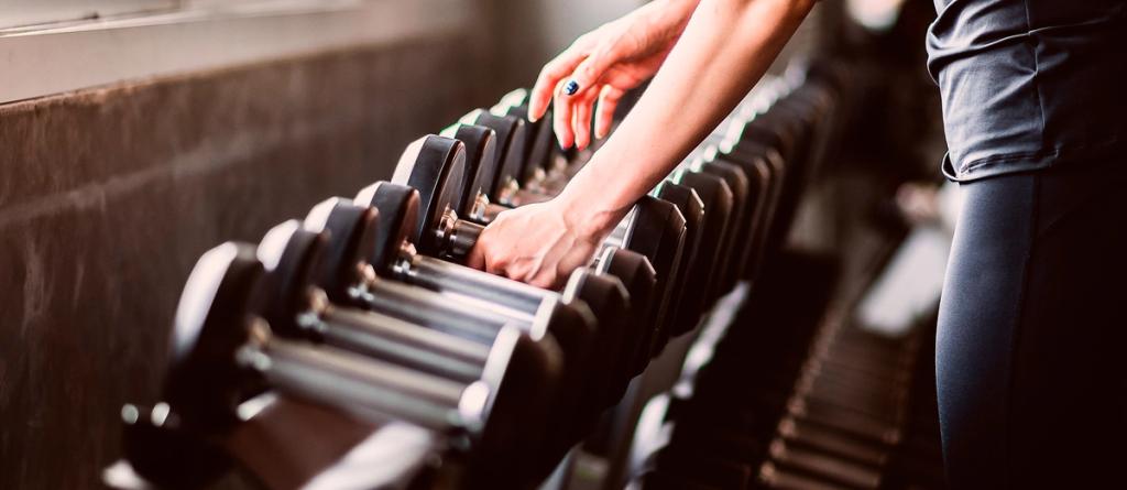 Woman's hand reaching for a dumbbell on a gym weight rack