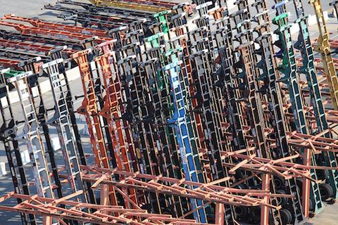 Rows of colorful steel truck chassis stored upright and tightly packed in an outdoor chassis pool depot yard.