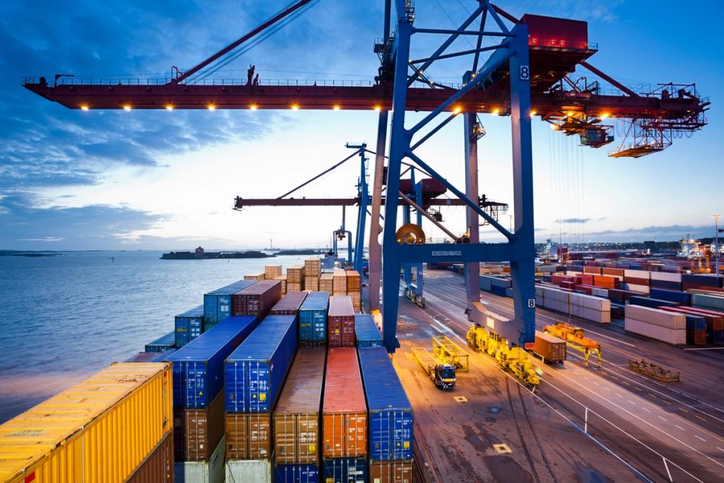 Container terminal at dusk with a ship-to-shore gantry crane over stacked colorful containers beside the waterfront
