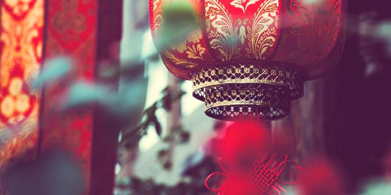 Ornate red and gold Chinese lantern hung among festive decorations with soft bokeh background