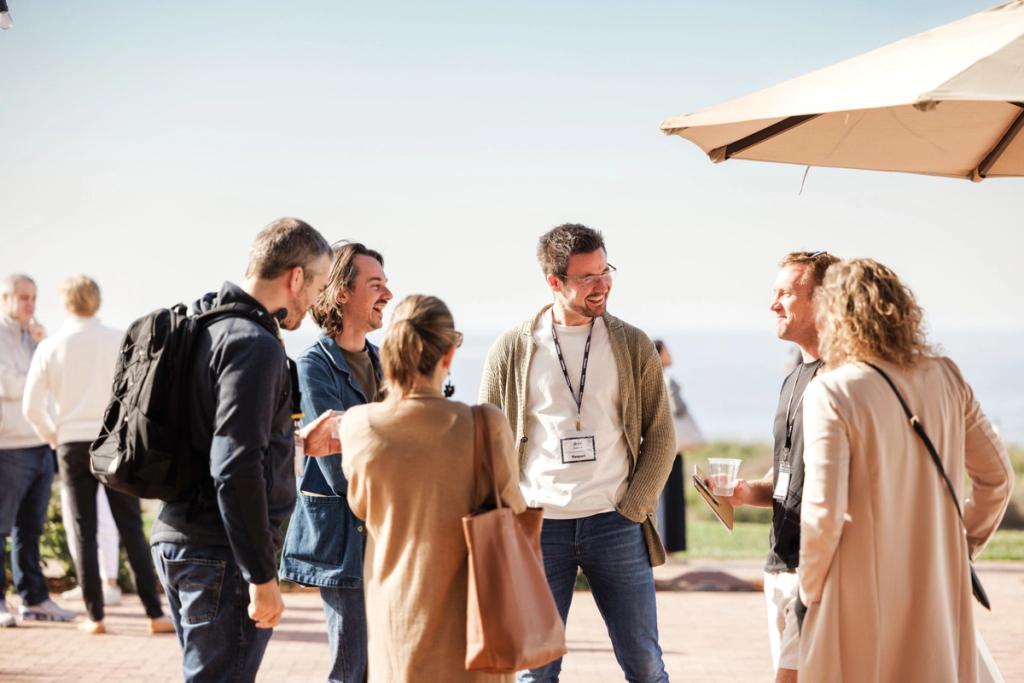Group of people engage in conversation during an outdoor event, with one person wearing a badge.