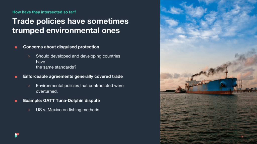 Slide on trade vs environmental policy beside a tanker emitting smoke at a port
