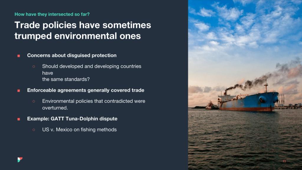 Slide on trade vs environmental policy beside a tanker emitting smoke at a port