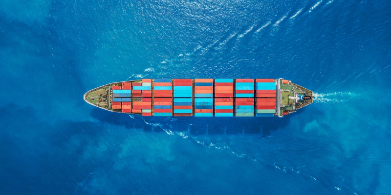 Aerial top-down view of a container ship loaded with cargo sailing on deep blue ocean