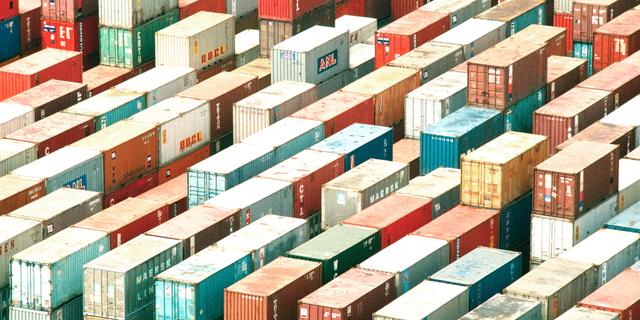 Aerial view of colorful shipping containers stacked in long rows at a port, representing capacity planning and forecasting