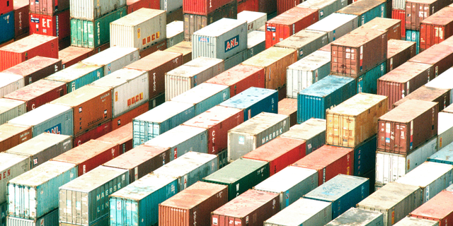 Aerial view of colorful shipping containers stacked in long rows at a port, representing capacity planning and forecasting
