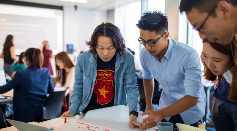 A team of colleagues collaborating around a whiteboard table in an open office