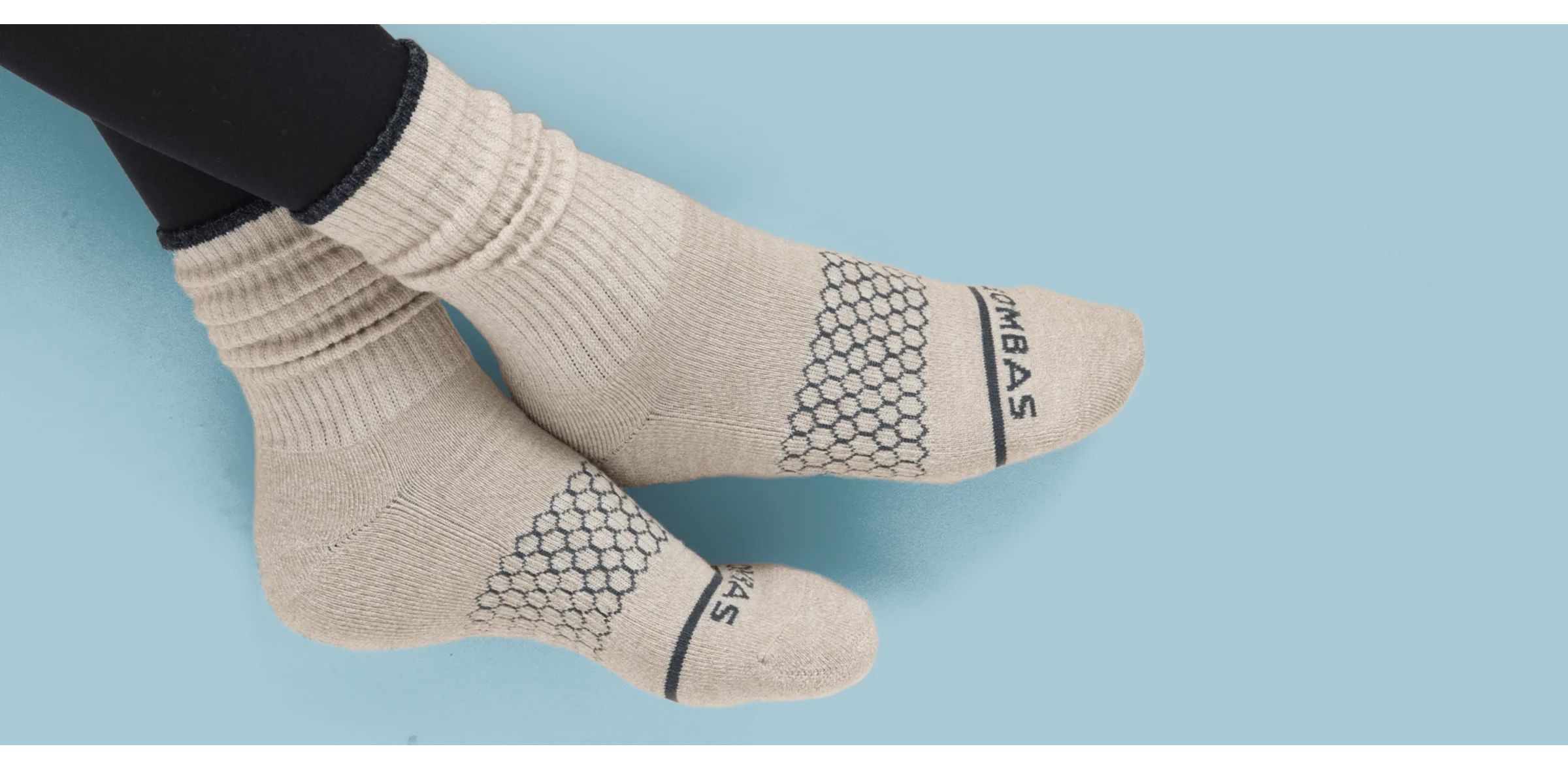 Person wearing cream-colored socks with honeycomb pattern and text design on the foot.