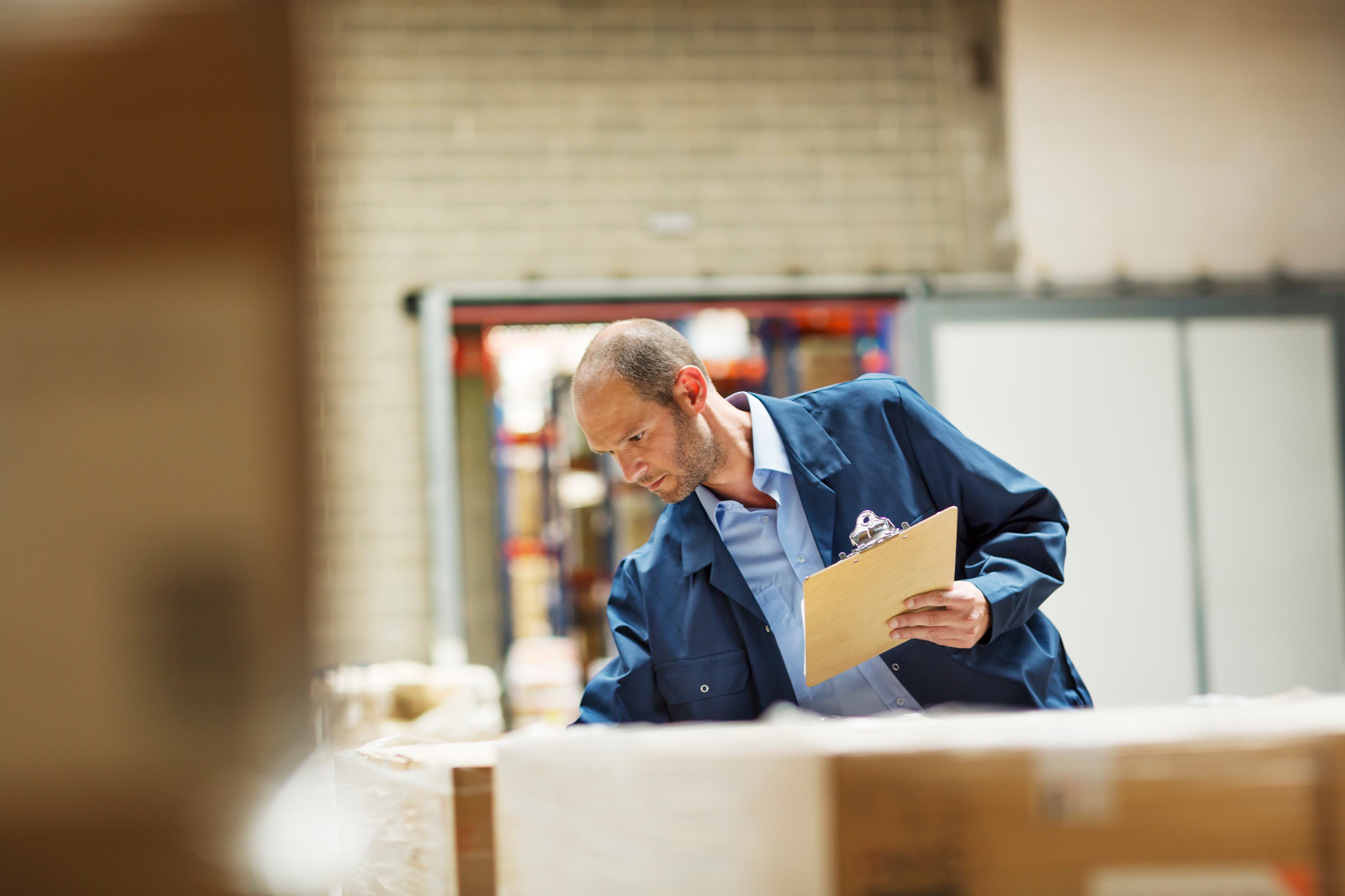 A worker reviewing shipment documentation on a clipboard