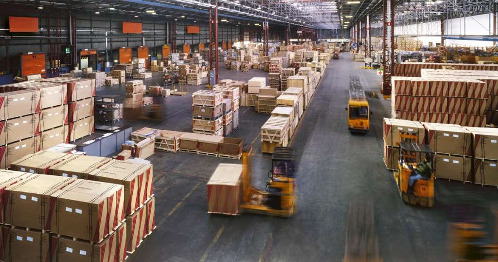 Forklifts moving palletized freight through a large distribution warehouse