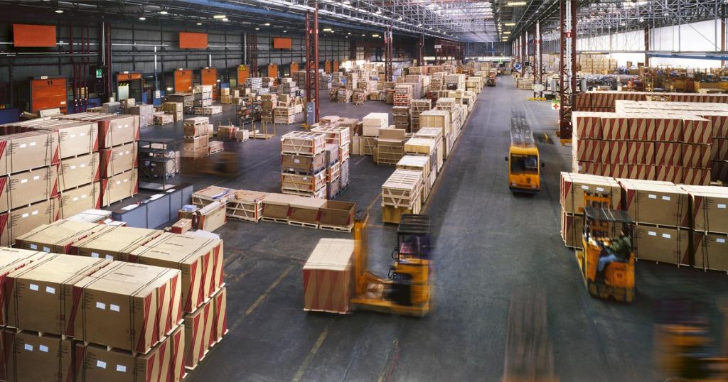 Forklifts moving palletized freight through a large distribution warehouse