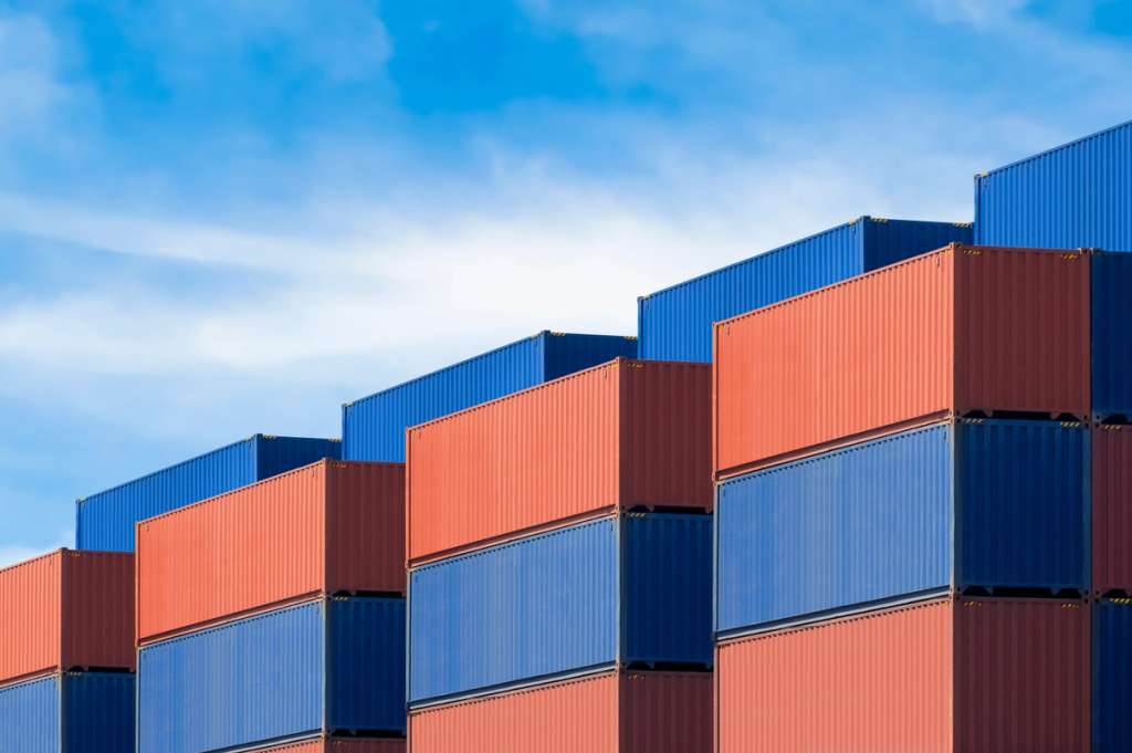 Stacked shipping containers arranged in a stepped pyramid formation against a sky backdrop.