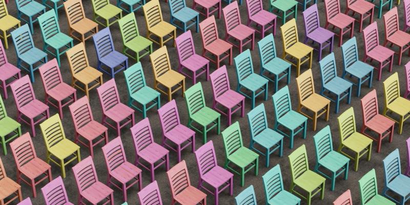 Overhead view of rows of identical wooden chairs each painted a different pastel color