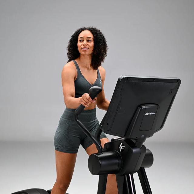 A person exercising on a Life Fitness cardio machine in a grey studio