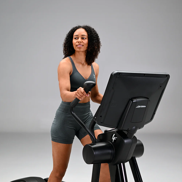 A person exercising on a Life Fitness cardio machine in a grey studio