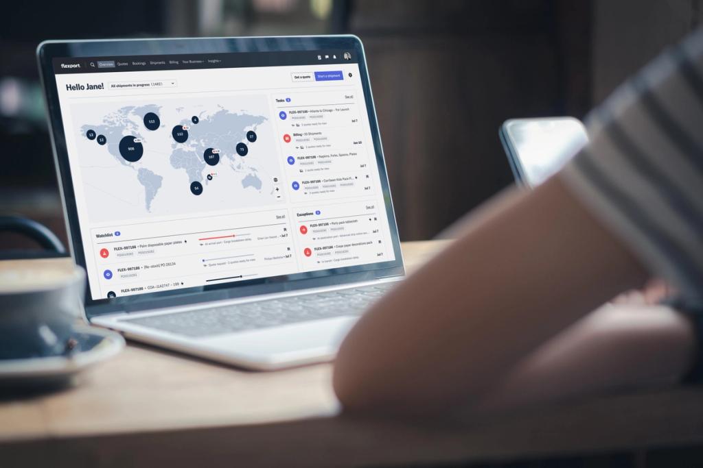Laptop showing Flexport platform dashboard with world map of shipments, tasks, and watchlist