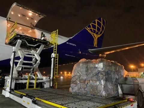 Shrink-wrapped pallet of relief supplies loaded onto a freighter aircraft tagged N452PA at night
