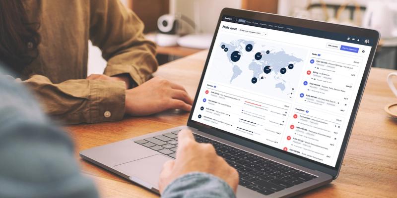 Person points at laptop showing Flexport platform dashboard with world map and shipment tasks