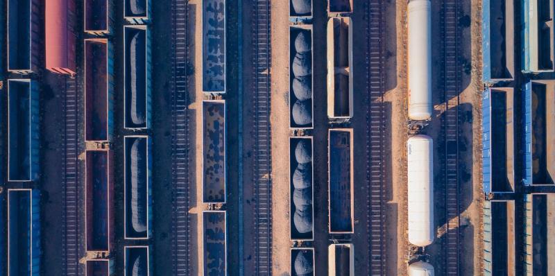 Overhead aerial view of parallel freight rail cars and tanker cars lined up in a rail yard