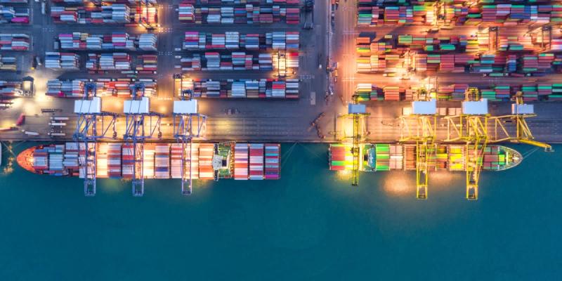 Aerial night view of a container port with gantry cranes loading ships and stacked containers
