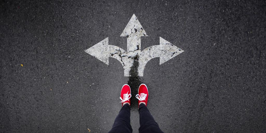 Person in red sneakers standing on asphalt at a painted three-way directional arrow