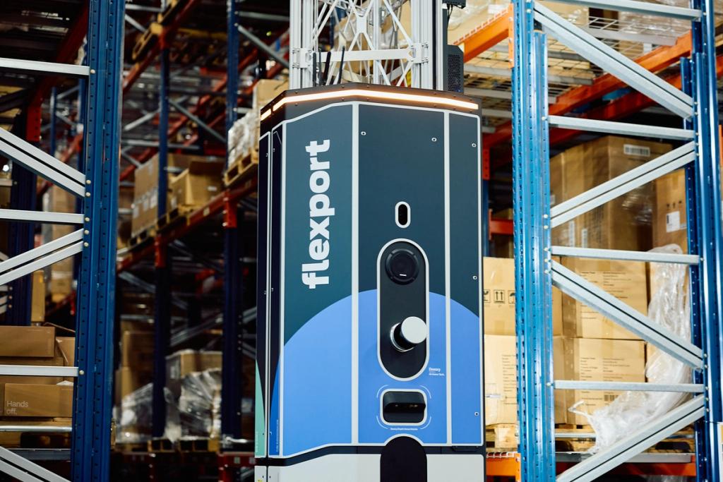Blue and black Flexport-branded autonomous robot navigating between tall warehouse pallet racks.