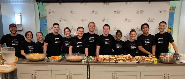Group of volunteers in I believe in I want to help t-shirts behind a buffet at Ronald McDonald House New York