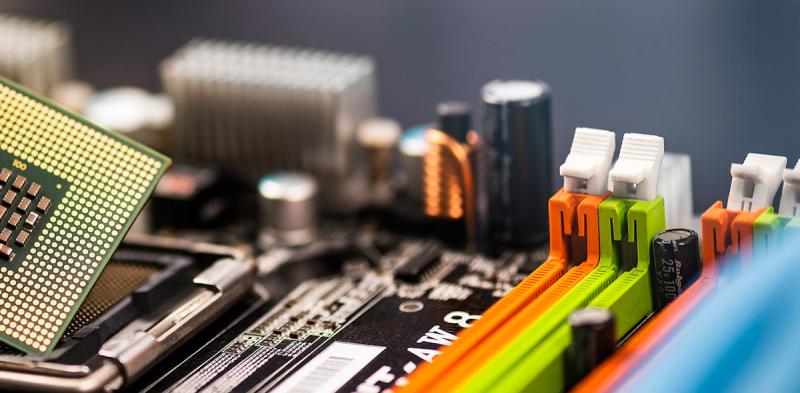 Close-up of a computer motherboard with a CPU chip, RAM slots, capacitors and heatsink