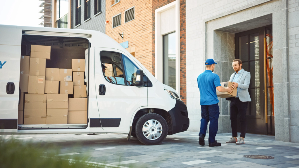 Delivery driver hands a package to customer at residential building entrance.