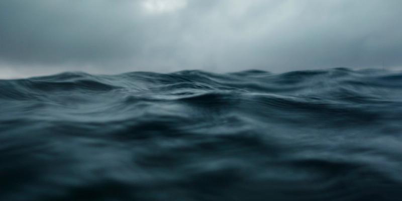 Close-up of dark, choppy ocean waves under a gray, overcast stormy sky