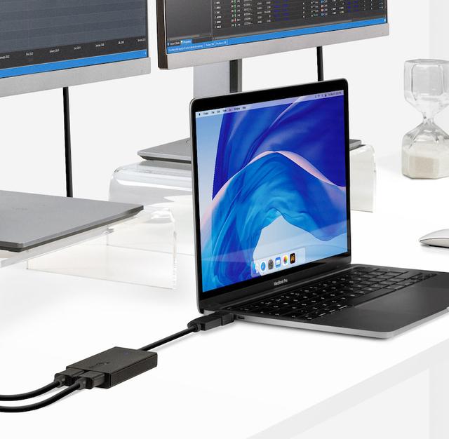 MacBook on a white desk connected to dual monitors via a Plugable docking adapter