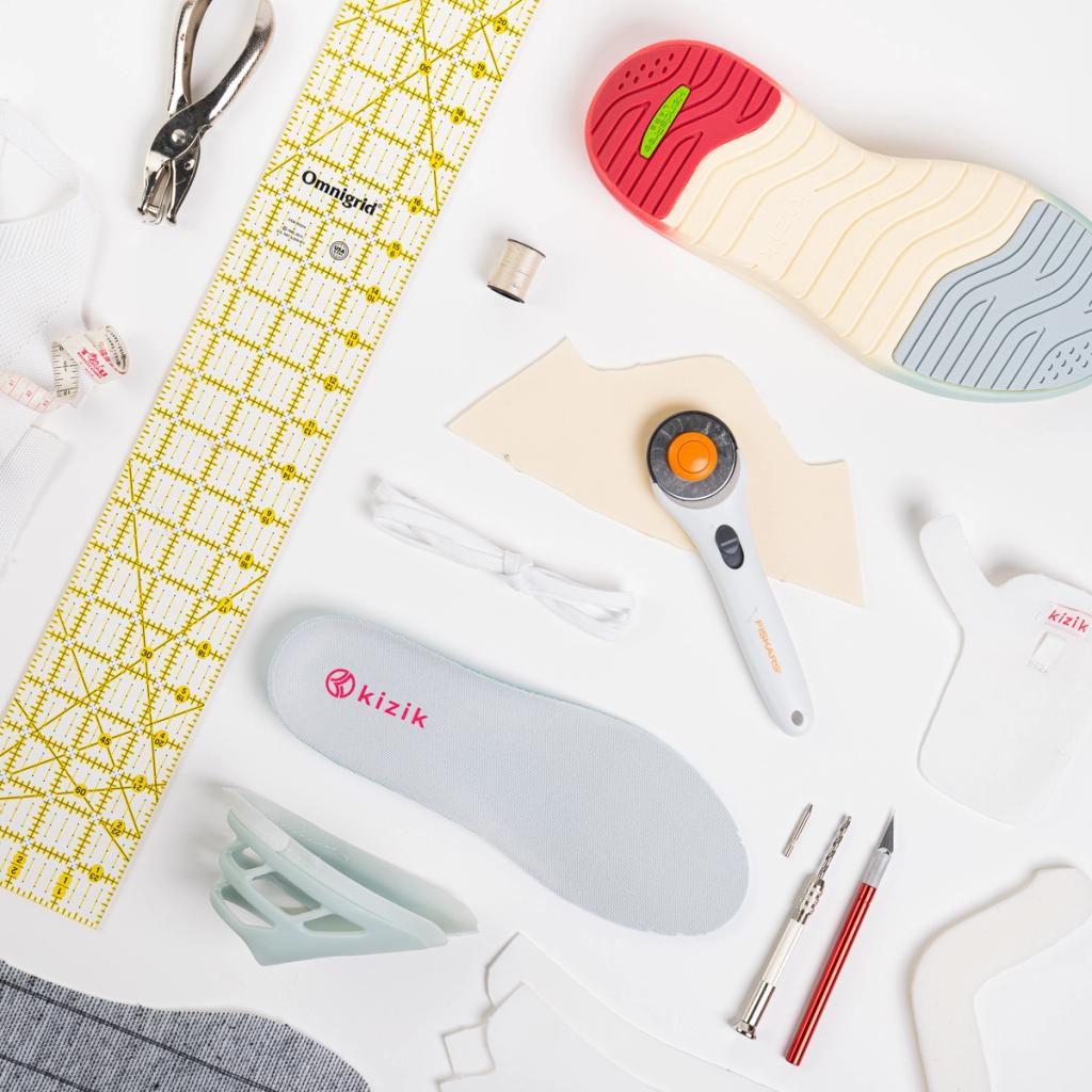 Flat-lay of Kizik shoe design tools including insole, ruler, rotary cutter and craft knives