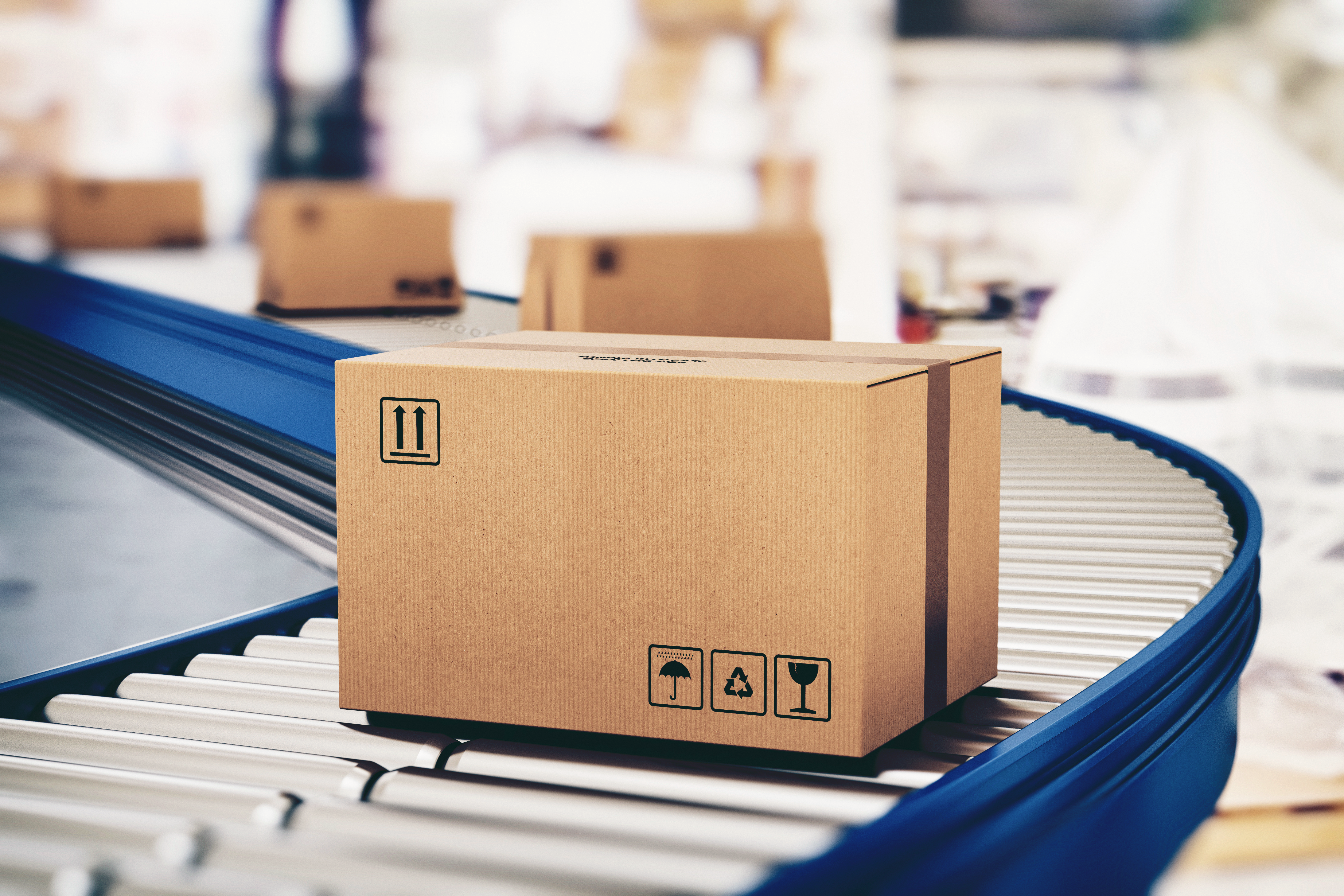 Cardboard shipping box moving along a blue roller conveyor in a warehouse