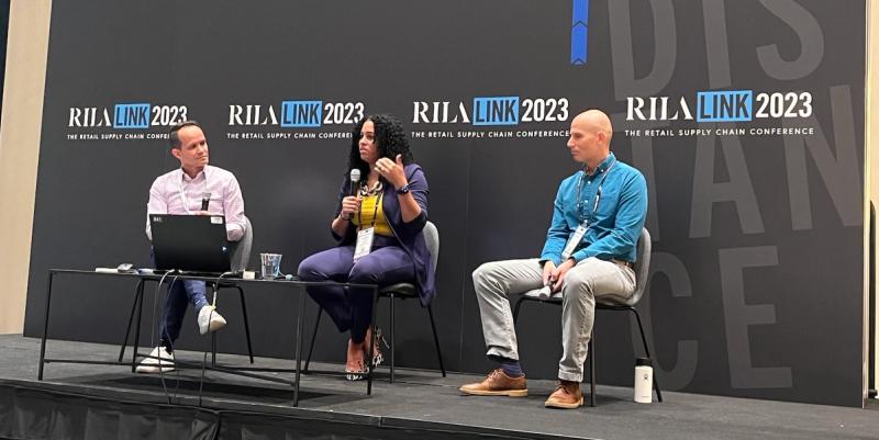 Three panelists seated on stage with a woman speaking into a mic before a RILA LINK 2023 backdrop