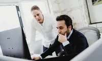 Close-up of a professional typing on a keyboard next to a laptop in a modern workspace, representing productivity, technology, and digital work environments.