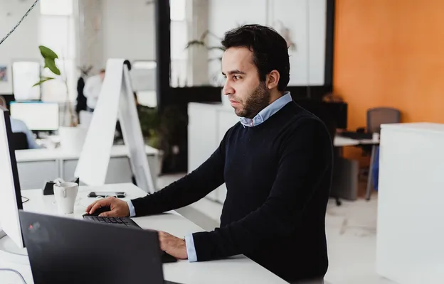 Zakelijke professional die informatie controleert op een laptop, wat analyse en focus uitbeeldt.