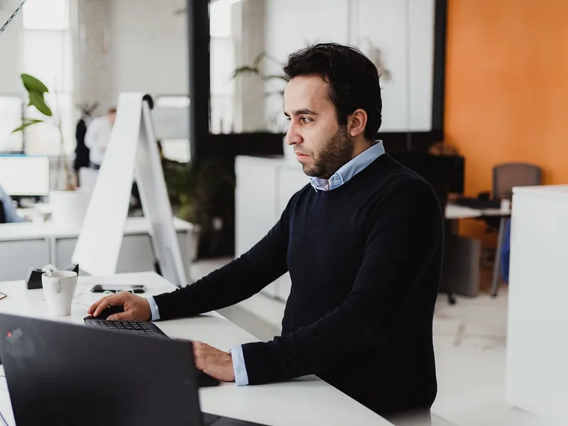 Business professional checking information on laptop, depicting analysis and focus.