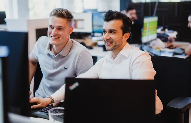 A professional man in a white shirt focuses on his laptop in a modern studio office, representing the focused and transparent nature of modern EU hiring practices.