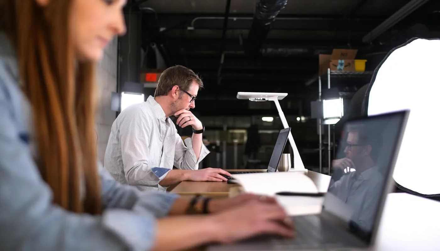 Een professionele man met een bril kijkt geconcentreerd naar zijn laptop in een moderne studio-omgeving; symbool voor de transparante en zorgvuldige aard van moderne EU-wervingsprocessen