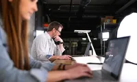A professional man in a white shirt focuses on his laptop in a modern studio office, representing the focused and transparent nature of modern EU hiring practices.