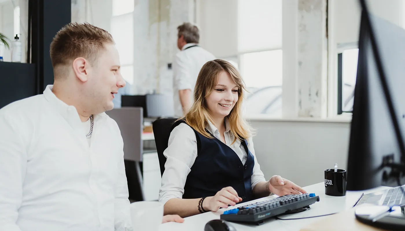 Two people at the office talking behind the desktop about work.